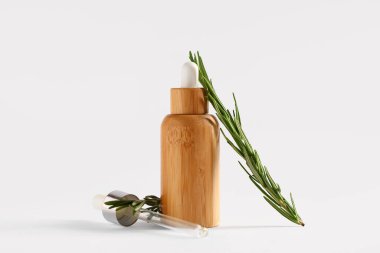 Beyaz arka planda izole edilmiş biberiye yağı şişesi ile bileşim, yakın plan