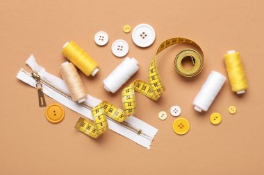 İplik makaralı kompozisyon, mezura ve bej arkaplan üzerindeki düğmeler