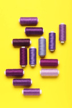 Sarı arkaplanda farklı iplik makaraları kümesi