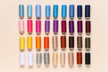 Bej arkaplanda birçok farklı iplik makarası