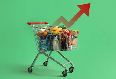 Yeşil arka planda farklı yiyeceklerle dolu alışveriş arabası.