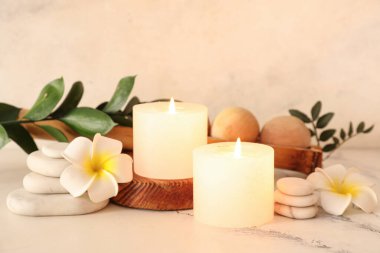 Ahşap tepsi, mumlar, çiçekler ve mermer masa üzerindeki spa taşlarıyla kaplıca kompozisyonu, yakın plan.