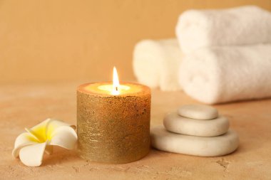 Altın mumlu spa kompozisyonu, bej arka planda spa taşları ve çiçek, yakın plan.