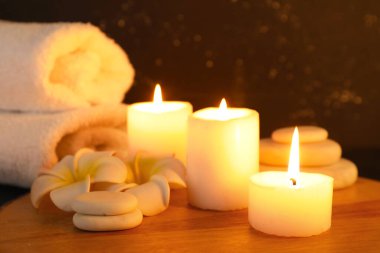 Mumlar, çiçekler ve kaplıca taşlarıyla kaplıca kompozisyonu ahşap masa, yakın plan.