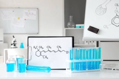 Tıbbi laboratuarda üzerinde formül olan kimyasal cam eşyalar ve pano.