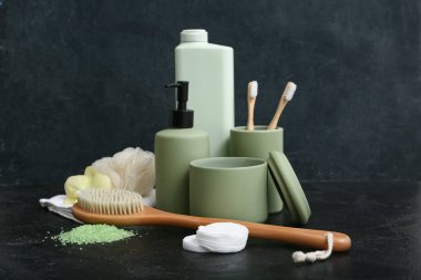 Deniz tuzu, masaj vücut fırçası ve siyah arka planda banyo malzemeleri.