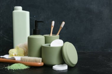 Deniz tuzu, masaj vücut fırçası ve siyah arka planda banyo malzemeleri.