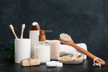 Banyo malzemeleri, masaj vücut fırçası, pamuk tomurcuklu sabun kutusu ve koyu kapsüller.