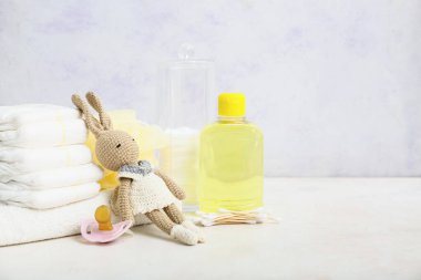 Tavşan oyuncağı, bebek bezi, havlu ve arka planda bebek kozmetik ürünü.