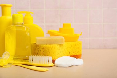 Tekne oyuncağı, emzik ve bej masadaki çocuklar için farklı banyo aksesuarları.