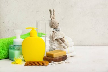 Bebek bezi, tavşan oyuncağı ve hafif arka plandaki bebek için farklı banyo aksesuarları.