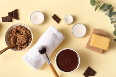 Bir kase çikolatalı deniz tuzu ve açık sarı arka planda yanan mumlarla kaplıca kompozisyonu