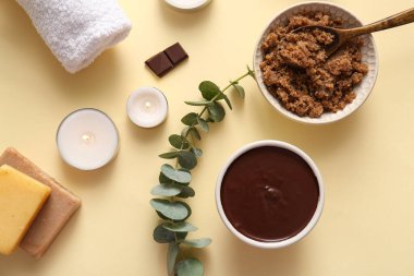 Bir kase çikolatalı deniz tuzu ve açık sarı arka planda yanan mumlarla kaplıca kompozisyonu