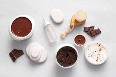 Beyaz arka planda erimiş çikolata, spa taşı ve tereyağı dolu spa kompozisyonu