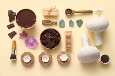 Kasede çikolata parçaları, pembe çiçekler ve soluk sarı arka planda yanan mumlarla kaplıca kompozisyonu.