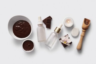 Erimiş çikolata kâseleriyle kaplıca kompozisyonu ve beyaz arka planda yanan mum