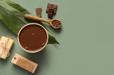 Yeşil arka planda bir kase erimiş çikolata, sabun ve yeşil yaprak içeren spa kompozisyonu