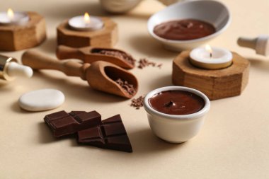 Kaplıca kompozisyonu, bir kase erimiş çikolata ve bej arka planda yanan mum, yakın plan.