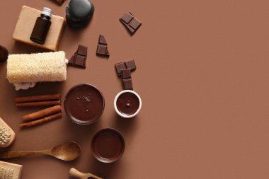 Kahverengi arka planda eritilmiş çikolata, tarçın ve kozmetik ürünleri içeren spa kompozisyonu