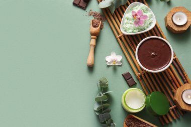 Bambu tepsisiyle spa kompozisyonu, bir kase erimiş çikolata, yanan mumlar ve yeşil arka planda çiçekler.