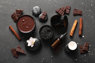 Güzel bir spa kompozisyonu, siyah arka planda erimiş çikolata ve spa taşları var.