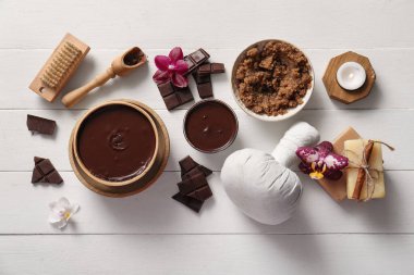 Beyaz ahşap arka planda eritilmiş çikolata ve çiçeklerle kaplıca kompozisyonu