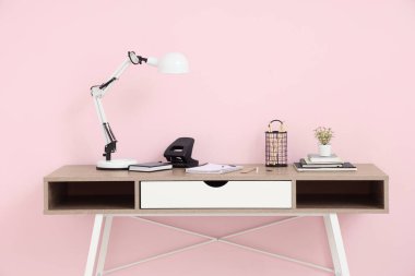 Masa lambasının, çiçeklerin ve ofis malzemelerinin bulunduğu modern iş yeri.