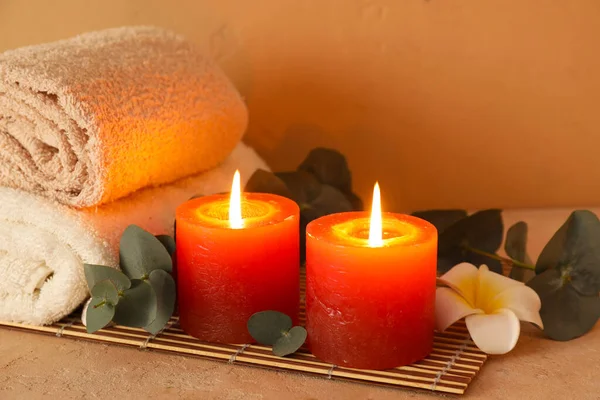 Kırmızı mumlar, çiçekler, okaliptüs dalları ve bej arka planda hasır kaplama, yakın plan