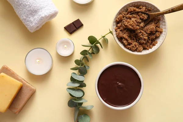 Bir kase çikolatalı deniz tuzu ve açık sarı arka planda yanan mumlarla kaplıca kompozisyonu