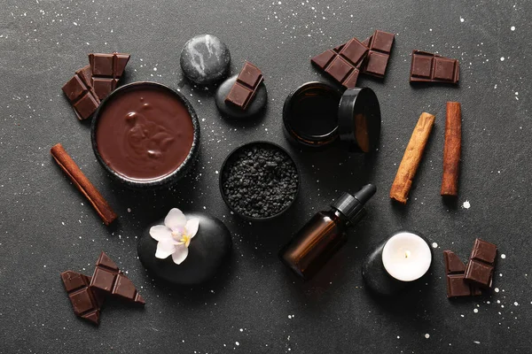 Güzel bir spa kompozisyonu, siyah arka planda erimiş çikolata ve spa taşları var.
