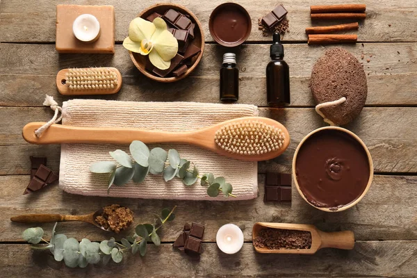 Erimiş çikolata kaseleri ve ahşap arka planda masaj vücut fırçası olan güzel bir spa kompozisyonu.