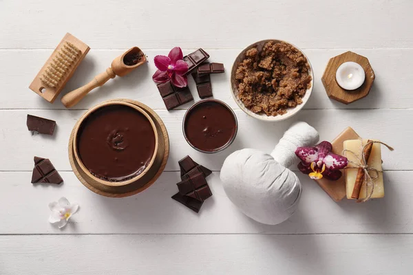 Beyaz ahşap arka planda eritilmiş çikolata ve çiçeklerle kaplıca kompozisyonu