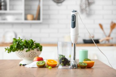 Modern blender ve taze malzemeler mutfaktaki ahşap masada.