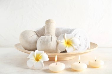 Mumlarla, bitki torbalarıyla ve açık arkaplanlı çiçeklerle güzel bir spa kompozisyonu.