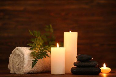Mumlarla, spa taşlarıyla ve ahşap arka planda havluyla güzel bir kompozisyon.