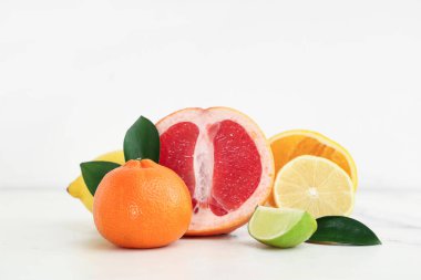 Beyaz arka planda farklı lezzetli narenciye meyveleri, yakın plan.