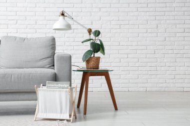 Oturma odasının içinde kanepe, lamba ve masa beyaz tuğla duvarın yanında, yakın plan.