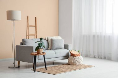 Oturma odasının içinde yer lambası, merdiven ve bej duvarın yanındaki kanepe.