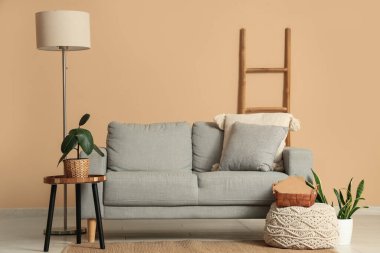 Oturma odasının içinde yer lambası, merdiven ve bej duvarın yanındaki kanepe.