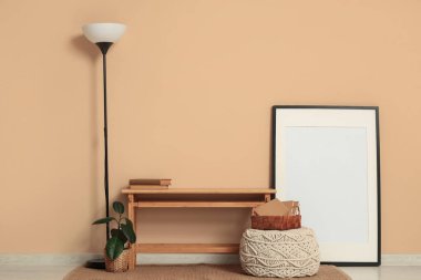 Oturma odasının içindeki bej duvarın yanında yer lambası, bank ve fotoğraf çerçevesi.