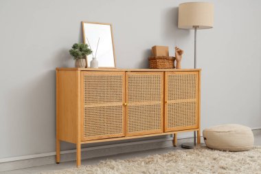 Oturma odasının iç tarafındaki gri duvarın yanındaki çekmeceler ve lamba, yakın plan.