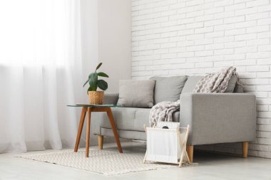 Rahat bir kanepe ve oturma odasındaki beyaz perdelerin yanındaki masa.