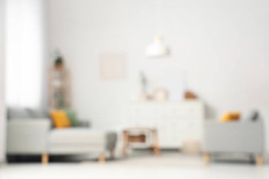 Oturma odasının bulanık manzarası, kanepeler ve beyaz duvarın yanındaki masa.