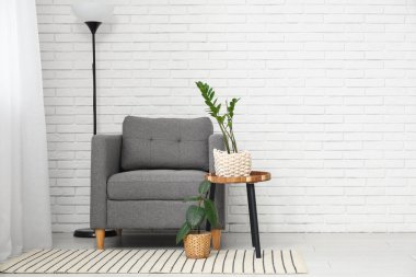 Koltuk ve zemin lambası oturma odasının içindeki beyaz tuğla duvarın yanında.