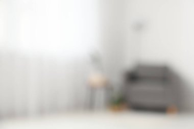 Beyaz duvarın yanında koltuğu olan oturma odasının bulanık görüntüsü