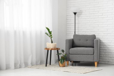 Koltuk ve yer lambası pencerenin yanında, oturma odasında perde var.