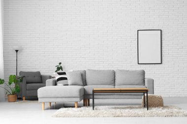 Koltuk ve masa beyaz tuğla duvarın yanında, oturma odasının içinde.