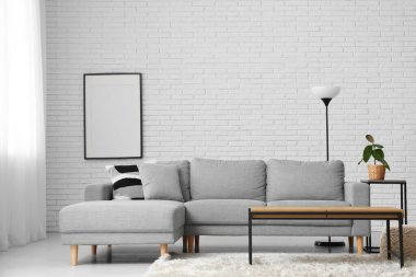 Oturma odasının içindeki beyaz tuğla duvarın yanındaki masa ve kanepe.