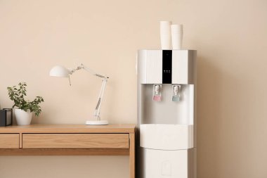 Ofiste bej duvarın yanında kağıt bardakları ve işyeri olan modern su soğutucusu, yakın plan.