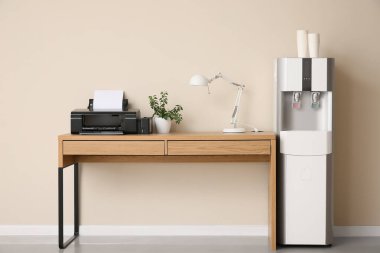 Ofiste bej duvarın yanında kağıt bardakları ve işyeri olan modern su soğutucusu.